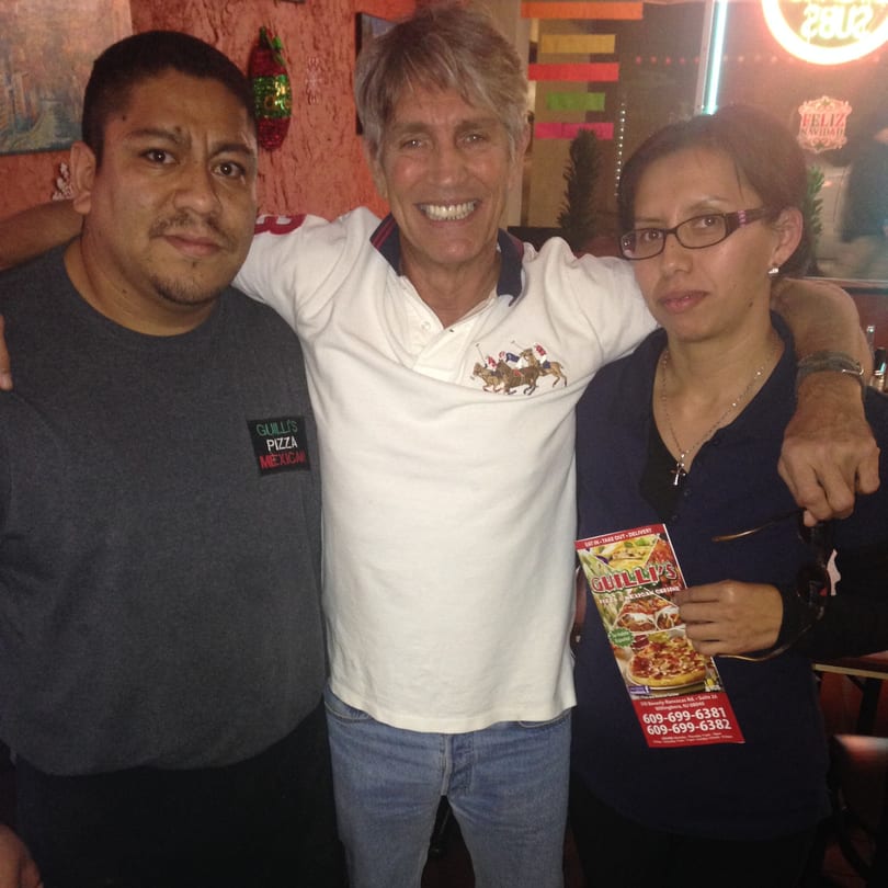 Three smiling people, two men and one woman, pose together inside Guilli's Authentic Mexican Cuisine.