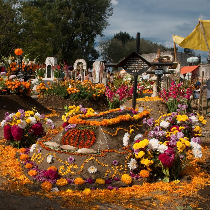 A cemetery grave adorned with marigolds, flowers, and offerings for Day of the Dead.